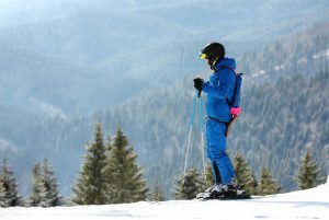 Man skiing on snowy hill in mountains, space for text. Winter vacation