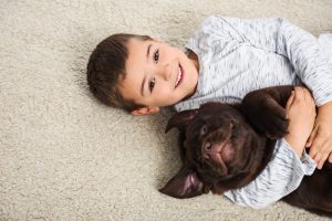 Little boy with dog lying on floor, top view