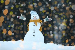 Adorable smiling snowman and blurred Christmas lights on backgro