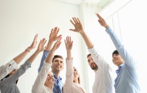 People raising hands together indoors. Unity concept