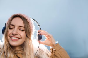 Young woman with headphones listening to music outdoors. Space for text